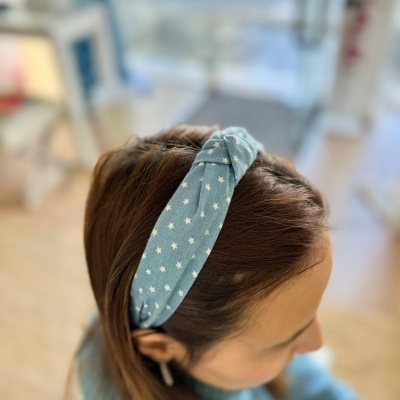 Diadema azul claro com estrelas brancas numa pessoa com cabelo castanho.