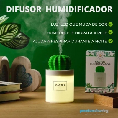 Difusor humidificador branco com topo em forma de cacto verde sobre mesa de madeira com decoração e caixa ao lado