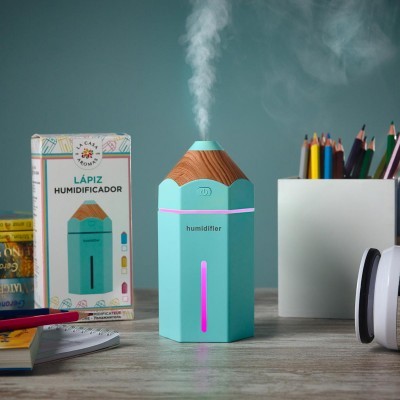 Humidificador em forma de lápis azul turquesa com topo em madeira emitindo vapor, com embalagem e lápis de cor ao fundo
