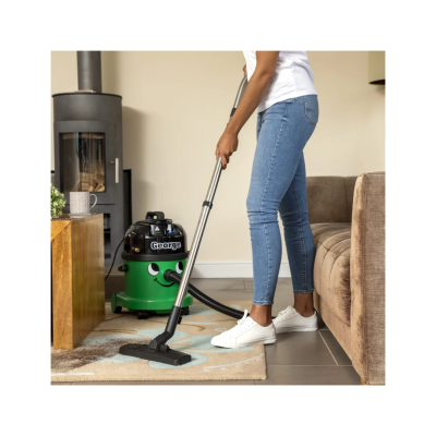 aspirador de pó verde e preto George numa sala com sofá e lareira