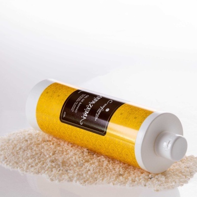 Frasco amarelo e branco com rótulo preto de gel de banho sobre grãos brancos