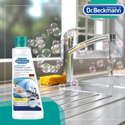 Frasco de detergente Dr. Beckmann para aço inoxidável junto a uma pia inox com bolhas e torneira
