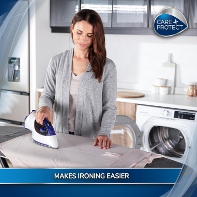 Mulher a passar a ferro roupa num ambiente doméstico com máquina de lavar ao fundo