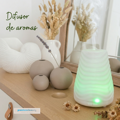 Difusor de aromas branco com luz verde num balcão de madeira com vasos e flores secas
