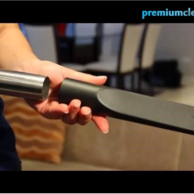 Mão segurando acessório para aspirador preto em ambiente de interior