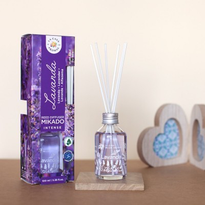 Frasco de difusor de aroma lavanda com varas ao lado da caixa roxa com imagens de lavanda.