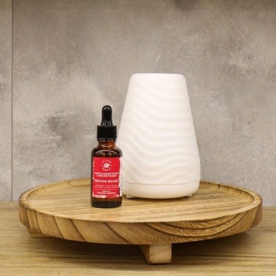 Difusor de aroma branco com base de madeira e frasco de óleo aromatizado com rótulo vermelho