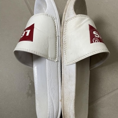 Par de chinelos desportivos slide brancos com logótipo vermelho, um novo e outro usado com sujidade
