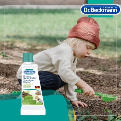 Criança com gorro vermelho a mexer na terra ao lado de frasco do produto Dr. Beckmann quitamanchas