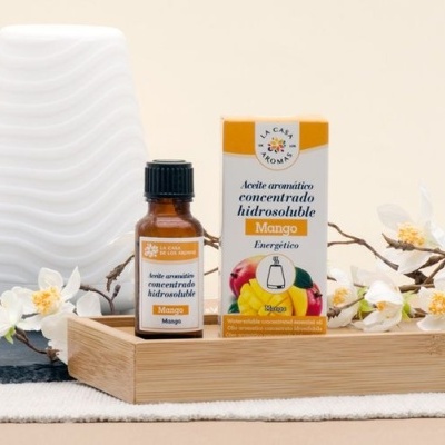 Óleo aromático concentrado de manga em frasco pequeno com caixa em bandeja de madeira e flores brancas