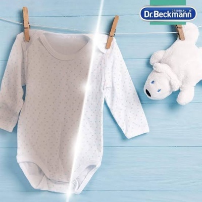 Body branco para bebé com pontos cinzentos pendurado num estendal azul com peluche e logótipo Dr. Beckmann