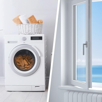 Máquina de lavar roupa com cesto e toalhas ao lado de janela aberta com vista para o mar