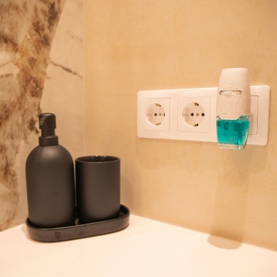 Dispenser automático branco com líquido azul na tomada ao lado de dispensador preto com copo preto