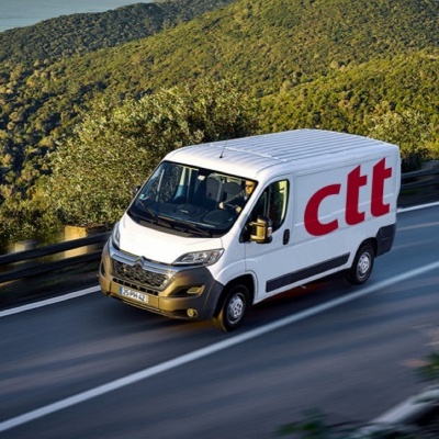 Carrinha branca com logotipo CTT numa estrada rodeada de vegetação