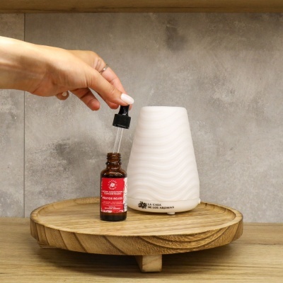 Frasco com gotário e difusor branco de aroma numa bandeja de madeira