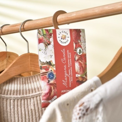 Etiqueta aromatizador natural La Casa Aromas pendurada em cabide de madeira no roupeiro.