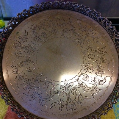 Tabuleiro redondo dourado com ornamentos florais e borda ornamentada