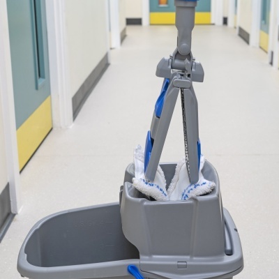 Baldes de limpeza cinzentos com esfregonas de microfibra branca e azul num corredor