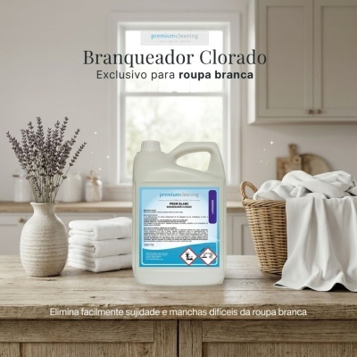 Branqueador clorado em recipiente plástico branco com rótulo azul numa mesa de cozinha com roupas brancas
