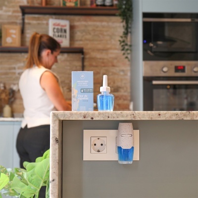 Ambientador elétrico azul e branco com embalagem azul numa bancada de cozinha.