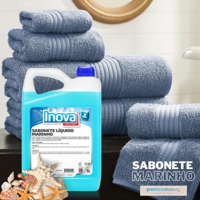 Garrafa de sabonete líquido Inova azul de 5 litros com toalhas cinzentas empilhadas e conchas decorativas
