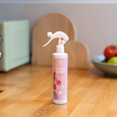Frasco de spray ambientador Frutos Rojos SWEET num balcão de madeira