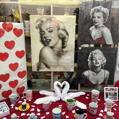 Vitrine com quadros de Marilyn Monroe, canecas decorativas, toalhas com corações vermelhos e panos dobrados em forma de cisnes.