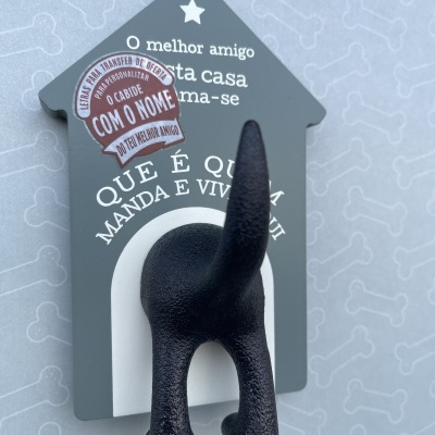 Pendurador de parede em forma de casa cinzenta com cauda de cão preta e texto em português
