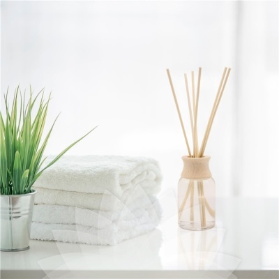 Toalhas brancas dobradas, difusor de aromas e planta verde num vaso metálico
