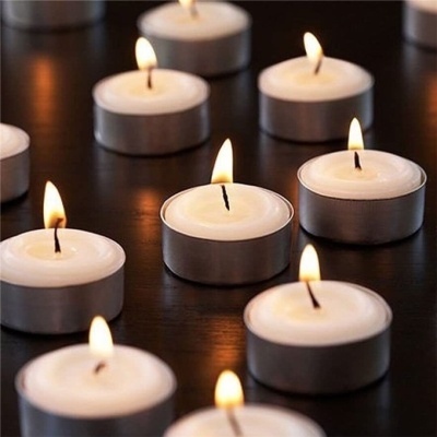 Velas tealight acesas em recipientes metálicos redondos sobre mesa escura