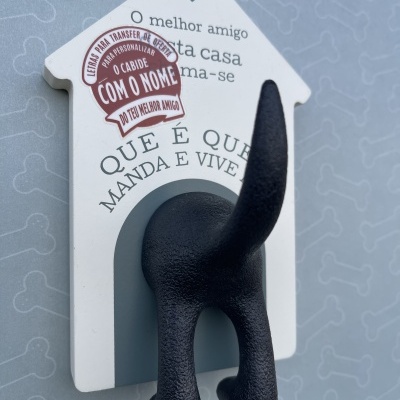 Cabide decorativo forma de casinha branca com cauda de cão preta e texto impresso.