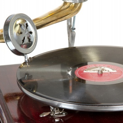 Gira-discos antigo com base de madeira e disco de vinil preto com etiqueta vermelha