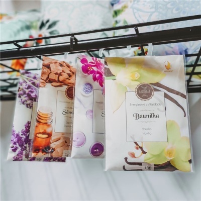 Pacotes de papel com aromas pendurados, destacando 'Baunilha' e motivos florais coloridos