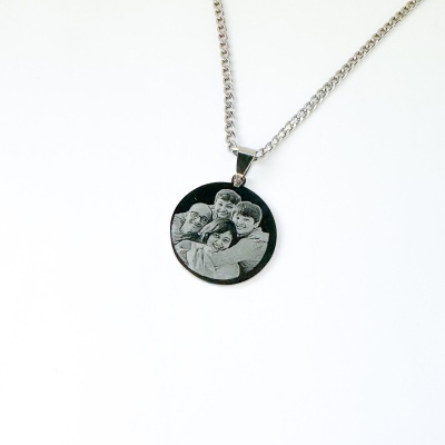 Colar com pendente redondo e gravura de quatro pessoas abraçadas.