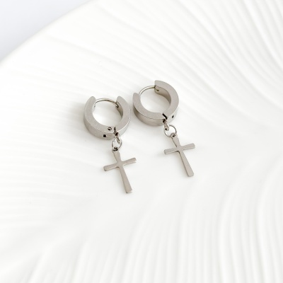 Brincos de argola prateados com cruz pendurada em fundo branco texturizado