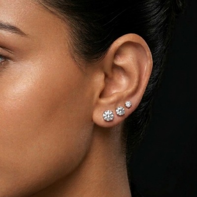 Orelha com três brincos de pedras brilhantes em várias dimensões