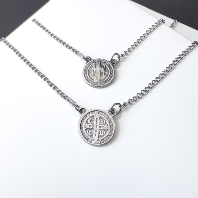 Duas colares de metal prateado com medalhas redondas e detalhes distintos.
