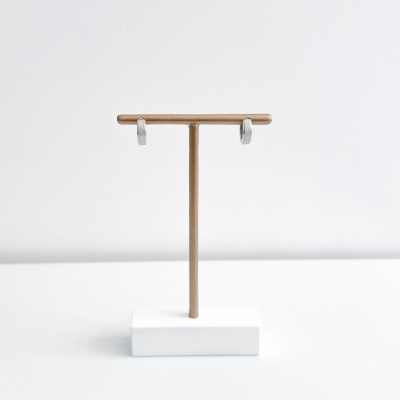 Brincos prateados em suporte castanho com base branca