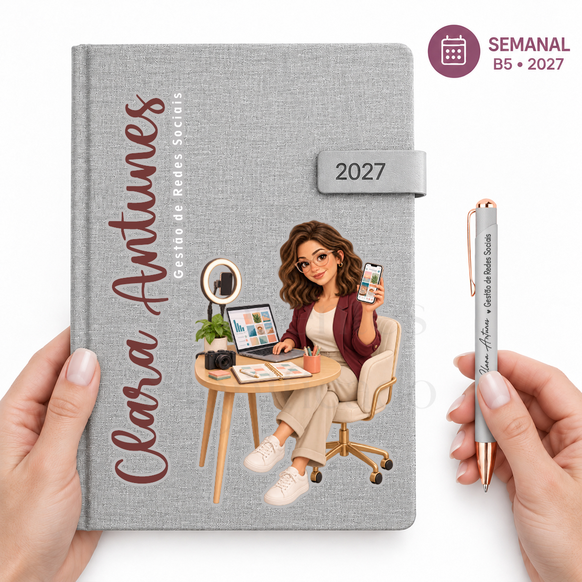 Agenda 2027 Personalizada HEROS — Semanal B5 Cinza Claro Livro cinza texturizado com ilustração de mulher a trabalhar em gestor de redes sociais, com caneta cinza e cobre e texto relacionado.