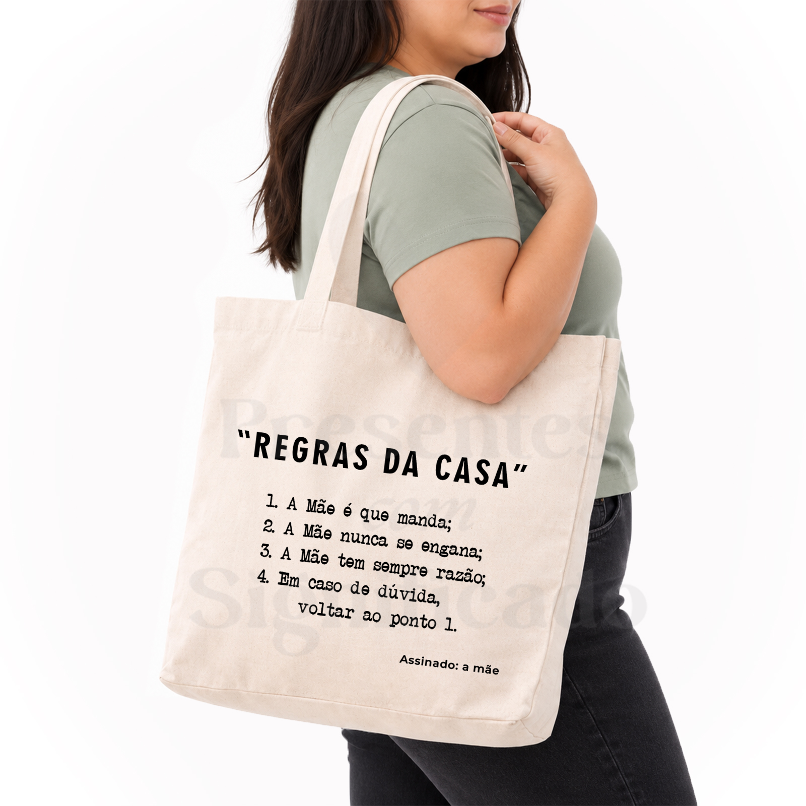 Saco/tote bag - Regras da Casa Mala tote de tecido cru com texto em português ao ombro de mulher com camisola verde