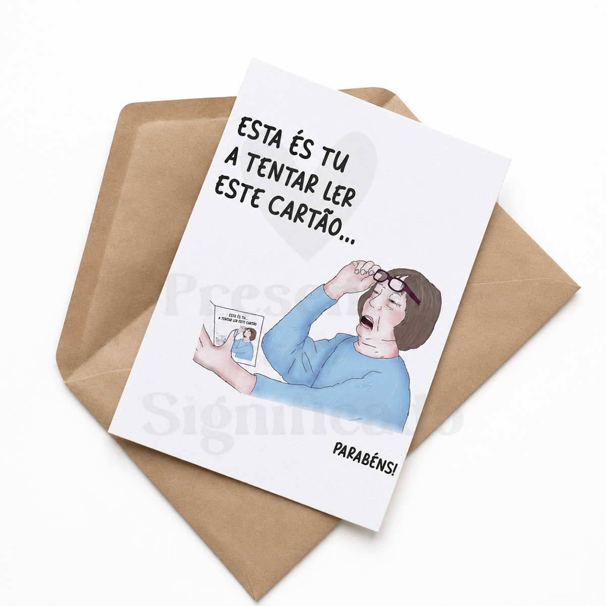 Postal de aniversário - Esta és tu... Cartão branco com ilustração de mulher a ler cartão menor, texto em português e envelope castanho claro.