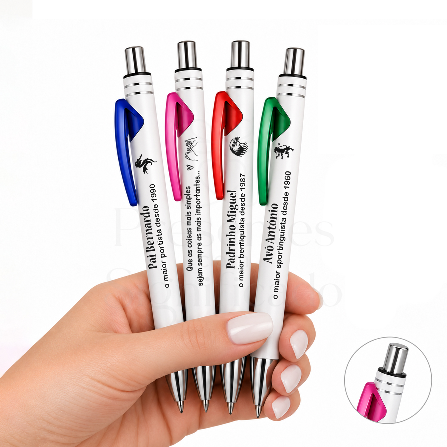 Caneta Personalizada Branca em Metal com Clipe Colorido Quatro canetas com clips coloridos e inscrições em português seguradas numa mão