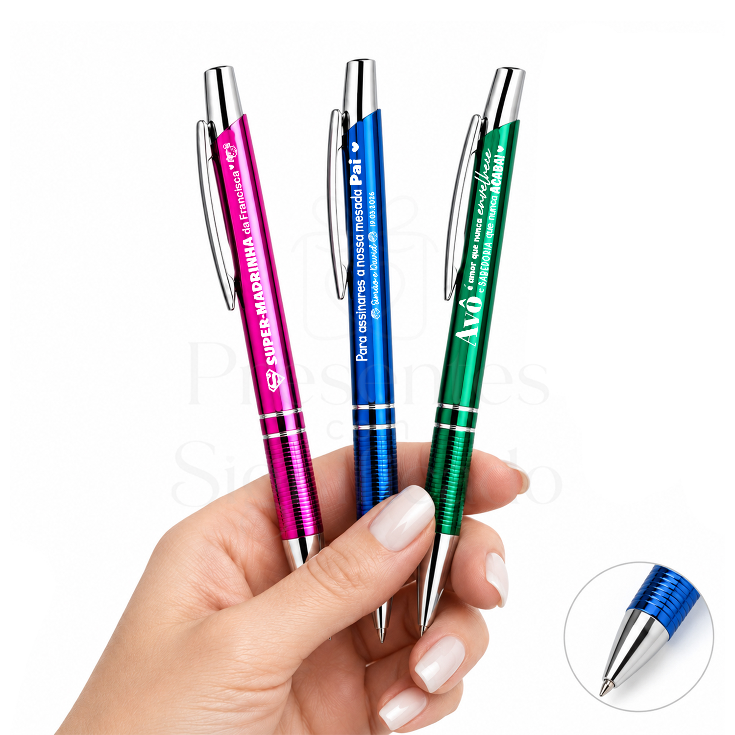Caneta Personalizada em Alumínio com Pega Texturada Três canetas coloridas metálicas com textos em branco seguradas por uma mão