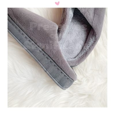 Chinelos cinza felpudos com sola preta sobre pelo branco.