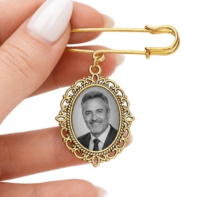 Alfinete de segurança dourado com pendente em moldura oval detalhada com fotografia a preto e branco