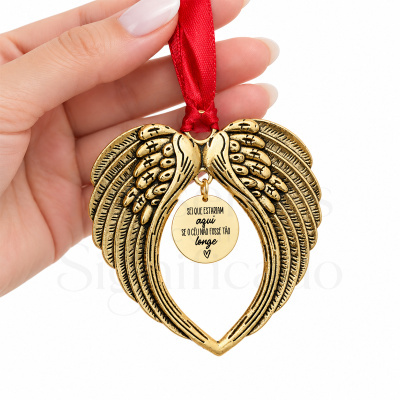 Adorno pendente dourado em forma de asas entrelaçadas com medalhão redondo e fita vermelha.