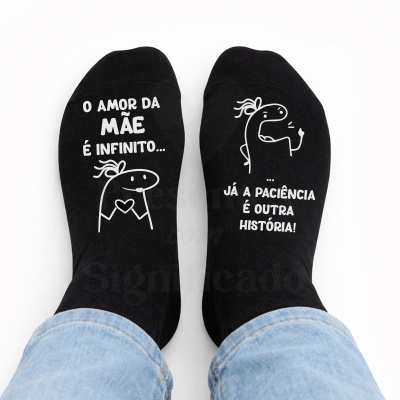 Par de meias pretas com texto humorístico e figuras desenhadas em branco.