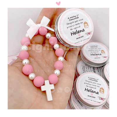 Pulseira rosa com cruz branca e etiquetas personalizadas para uma primeira comunhão.