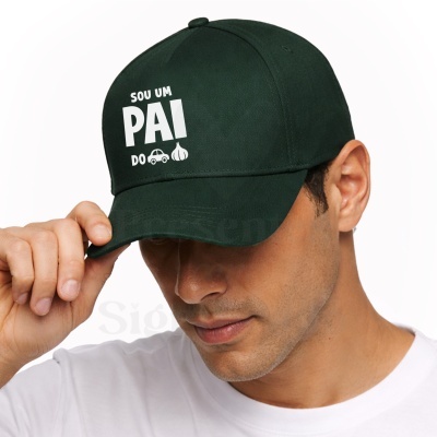 Boné verde escuro com texto e ícones brancos usado por homem de camisola branca