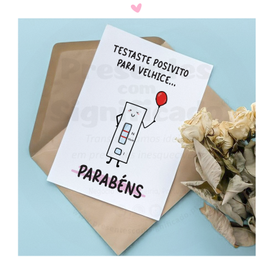 Cartão com mensagem de teste positivo para velhice e envelope castanho junto a flores secas